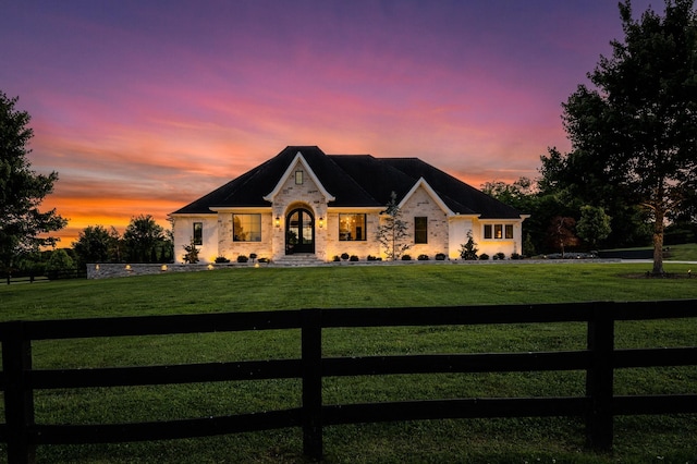 french provincial home with a lawn