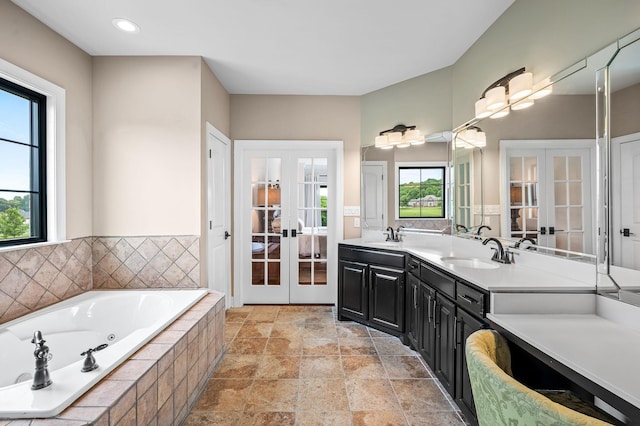 bathroom featuring vanity, tiled tub, and french doors