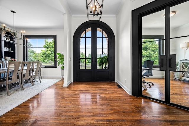 entryway featuring dark hardwood / wood-style flooring, french doors, ornamental molding, and an inviting chandelier