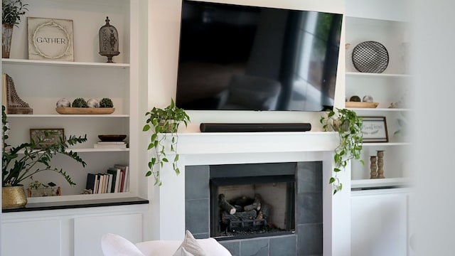 living room featuring a tile fireplace and built in features