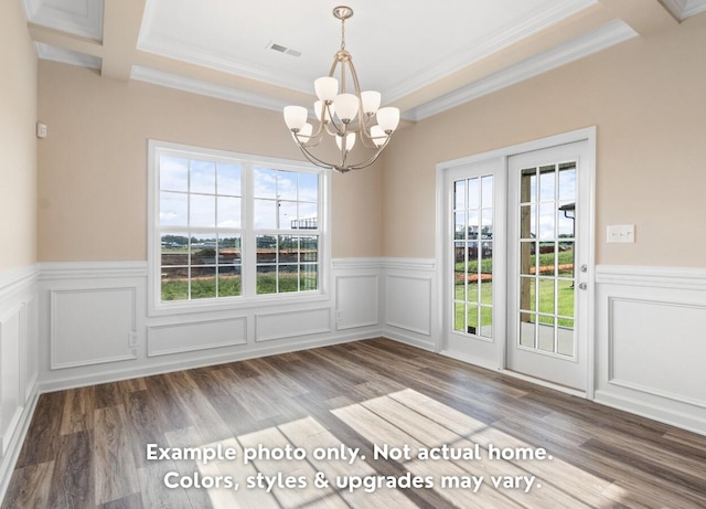 unfurnished dining area featuring crown molding, wood-type flooring, a wealth of natural light, and an inviting chandelier