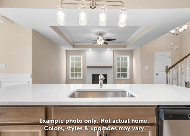 kitchen with a raised ceiling, dishwasher, sink, and ornamental molding