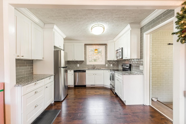 kitchen featuring white cabinets, stainless steel appliances, light stone countertops, and sink