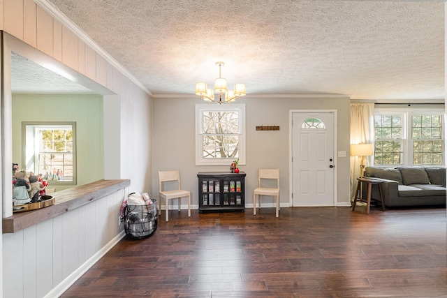 foyer with a chandelier, a healthy amount of sunlight, crown molding, and wood finished floors