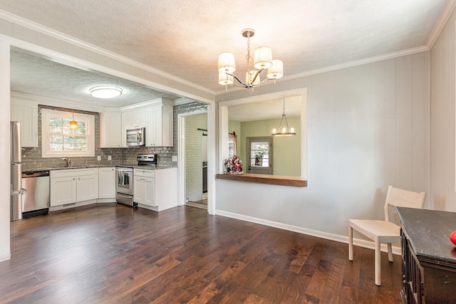 kitchen with stainless steel appliances, a healthy amount of sunlight, dark wood finished floors, and an inviting chandelier