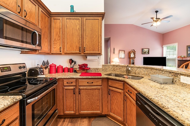 kitchen featuring light stone countertops, stainless steel appliances, vaulted ceiling, sink, and wood-type flooring