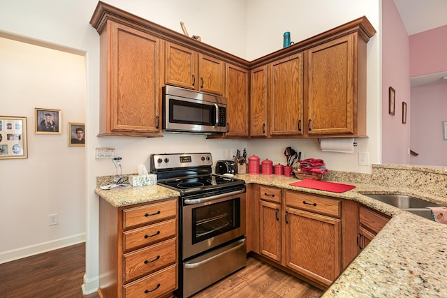 kitchen featuring light stone countertops, dark wood-type flooring, and stainless steel appliances