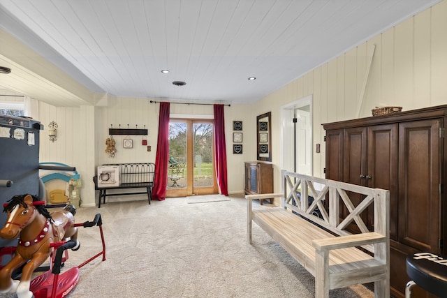 living area with wooden ceiling, light carpet, and wooden walls