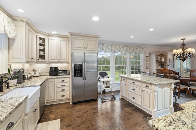 kitchen featuring a chandelier, appliances with stainless steel finishes, decorative light fixtures, and cream cabinets