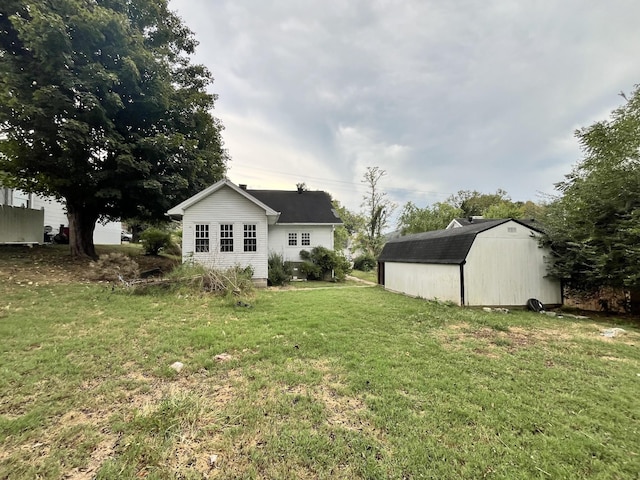 rear view of house with a yard, a storage shed, and an outbuilding