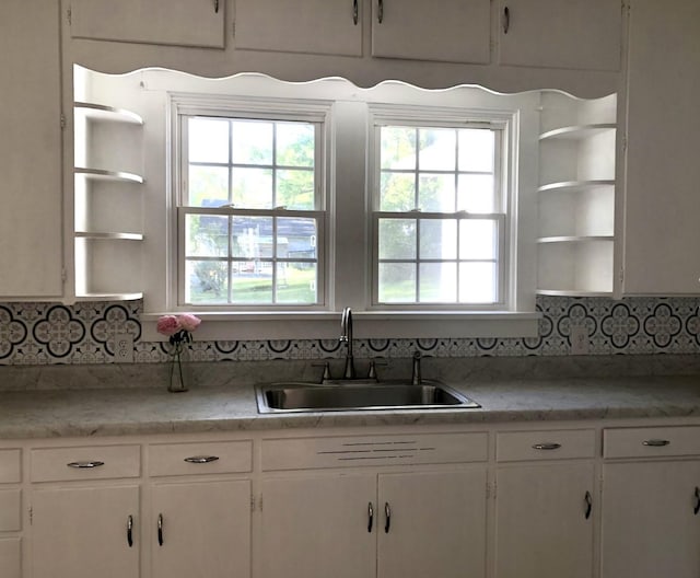 kitchen with light countertops, white cabinets, a sink, and open shelves