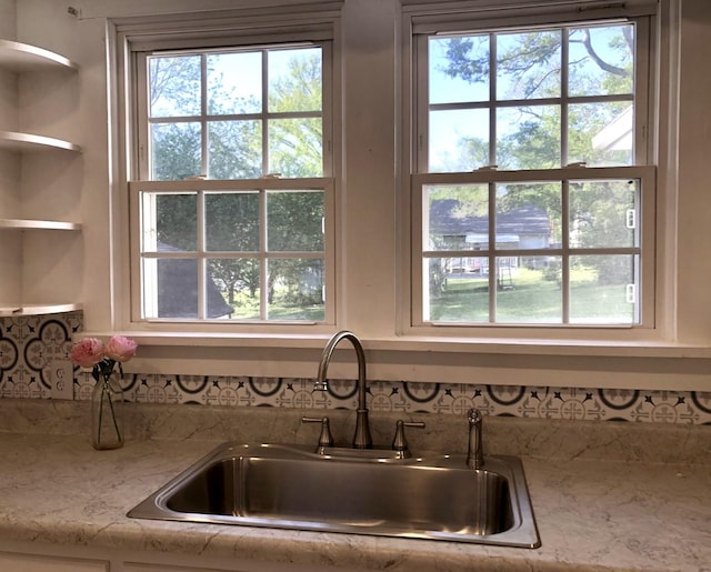 room details featuring light stone countertops, open shelves, and a sink