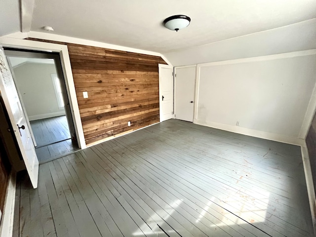 interior space featuring vaulted ceiling, dark wood finished floors, and wooden walls