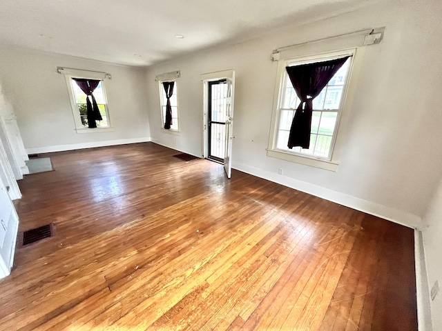 unfurnished living room featuring wood finished floors, visible vents, and baseboards