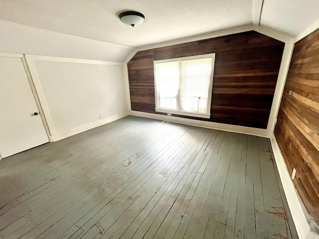 additional living space featuring lofted ceiling, wood walls, and wood finished floors