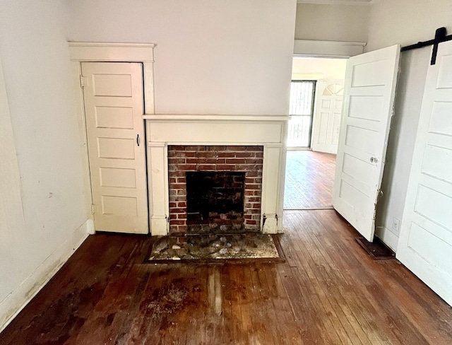 unfurnished living room with a brick fireplace, dark wood finished floors, and baseboards