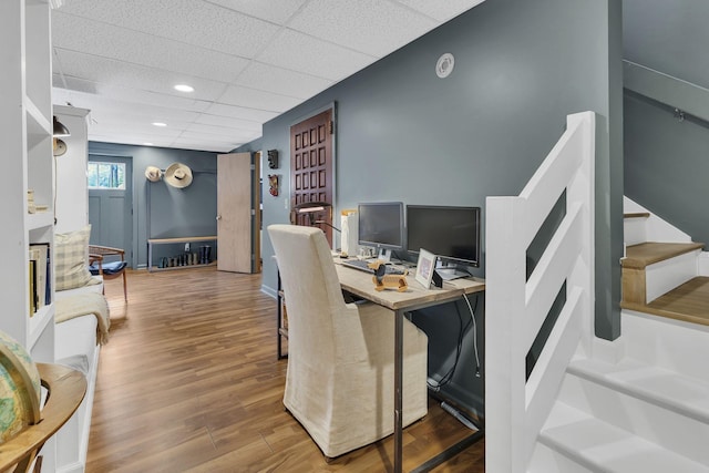 home office featuring wood-type flooring and a paneled ceiling