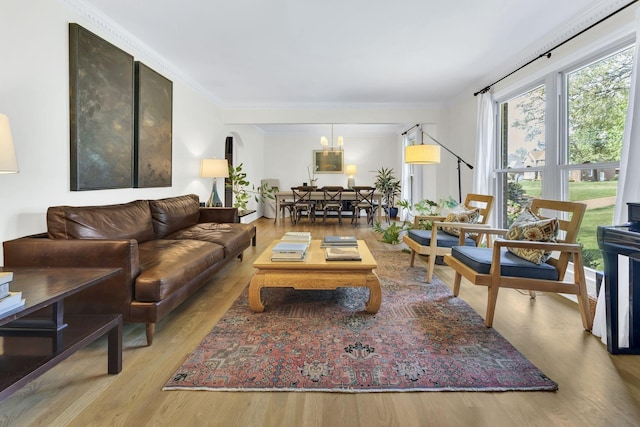 living room featuring an inviting chandelier, crown molding, and light hardwood / wood-style flooring