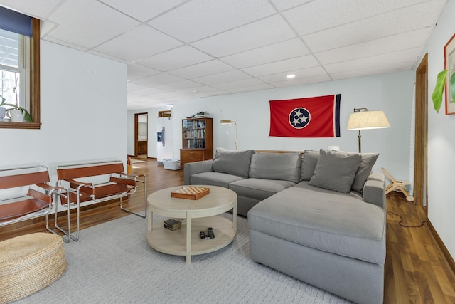 living room with hardwood / wood-style flooring and a paneled ceiling