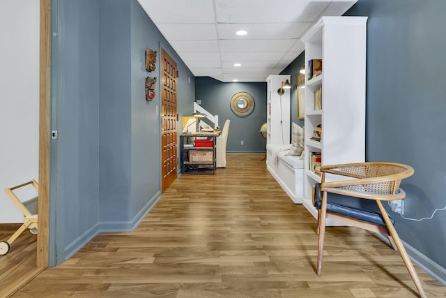 corridor with a paneled ceiling and light hardwood / wood-style flooring