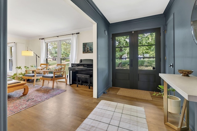 foyer entrance with crown molding, french doors, and light hardwood / wood-style floors