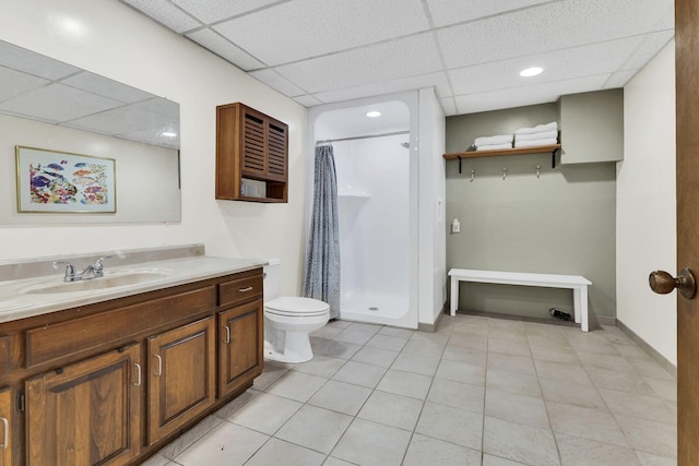 bathroom with walk in shower, vanity, toilet, and a drop ceiling