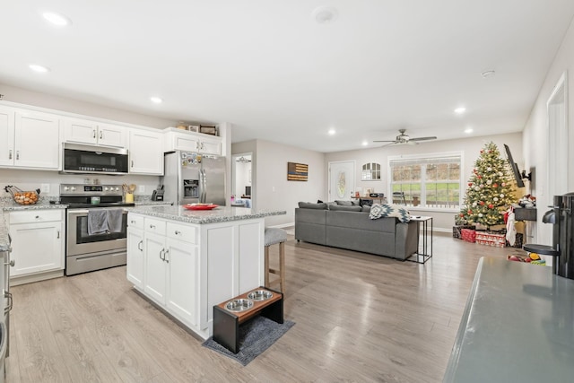 kitchen with white cabinets, appliances with stainless steel finishes, a center island, and ceiling fan