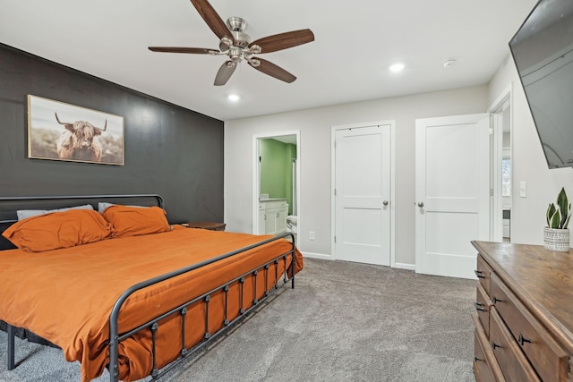 bedroom featuring ensuite bath, ceiling fan, and dark carpet