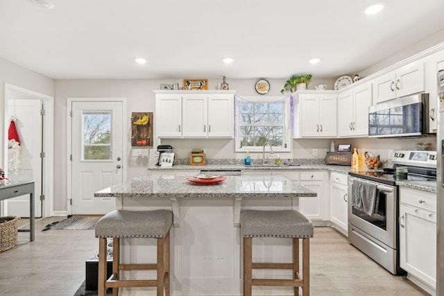 kitchen featuring white cabinets, a center island, a kitchen bar, and stainless steel appliances