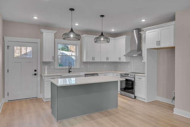 kitchen featuring a center island, wall chimney range hood, sink, white cabinetry, and stainless steel appliances