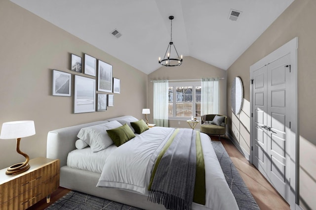 bedroom with wood-type flooring, vaulted ceiling, and a notable chandelier