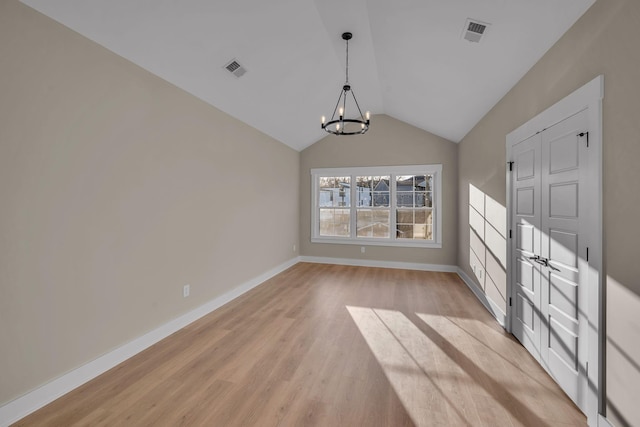 unfurnished dining area with light wood-type flooring, vaulted ceiling, and an inviting chandelier