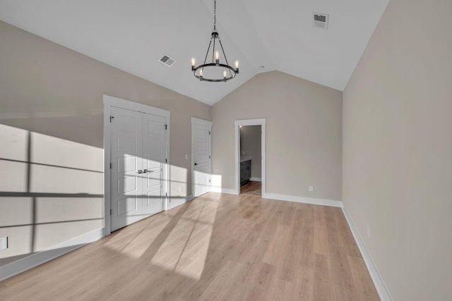 unfurnished room featuring lofted ceiling, light hardwood / wood-style flooring, and a notable chandelier