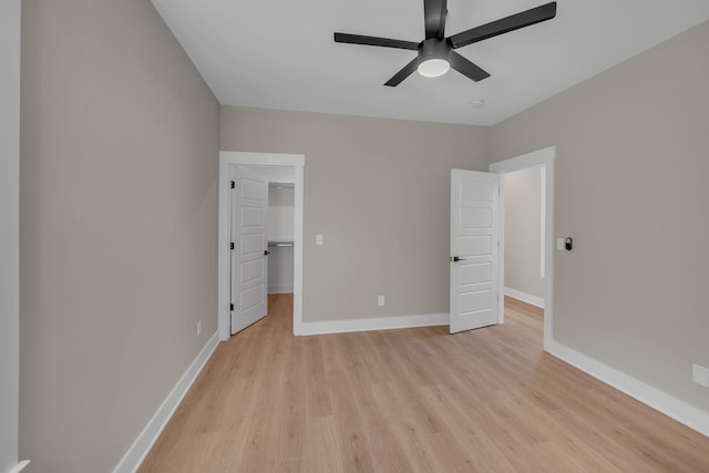 unfurnished bedroom with ceiling fan, light wood-type flooring, a spacious closet, and a closet