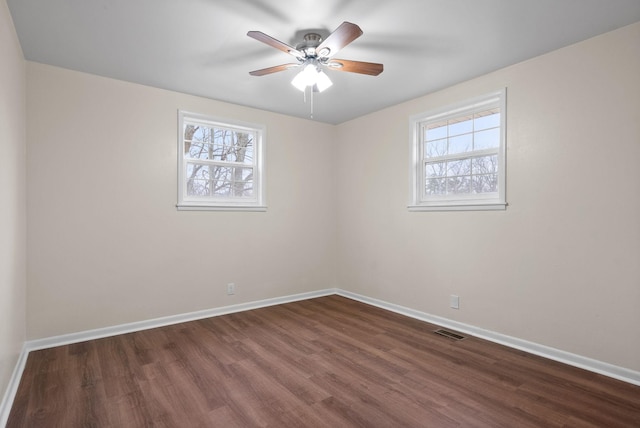 empty room featuring ceiling fan, plenty of natural light, and dark hardwood / wood-style floors