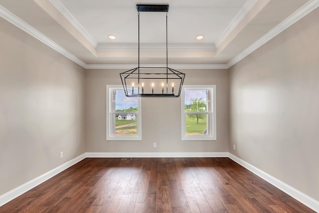 unfurnished dining area with crown molding, dark hardwood / wood-style floors, a tray ceiling, and a chandelier