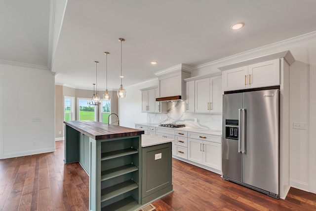 kitchen with a center island with sink, butcher block countertops, appliances with stainless steel finishes, hanging light fixtures, and white cabinets