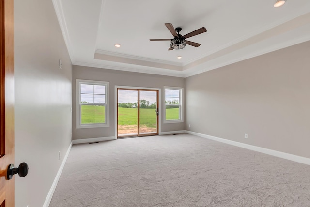 carpeted spare room with a raised ceiling, ceiling fan, and ornamental molding