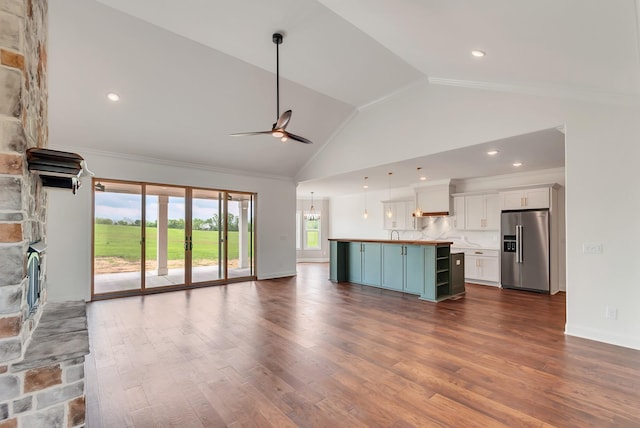 unfurnished living room featuring vaulted ceiling, ceiling fan with notable chandelier, wood-type flooring, and a stone fireplace