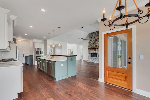 kitchen featuring decorative light fixtures, lofted ceiling, white cabinetry, a kitchen island with sink, and ceiling fan with notable chandelier