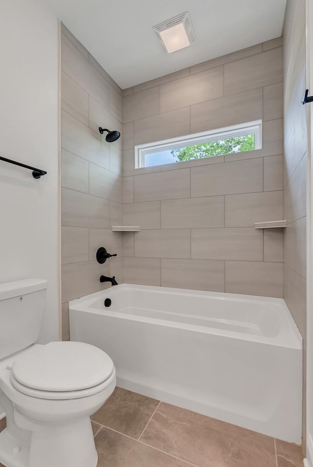 bathroom with tile patterned floors, toilet, and tiled shower / bath combo