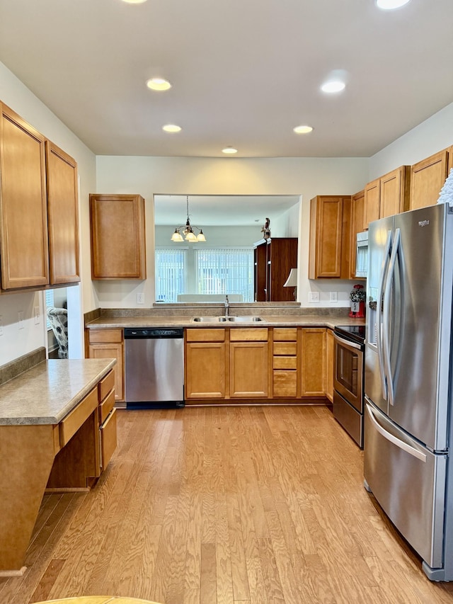 kitchen with sink, hanging light fixtures, a chandelier, appliances with stainless steel finishes, and light wood-type flooring