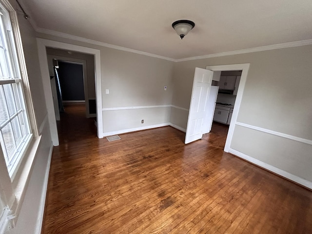 spare room featuring crown molding and dark wood-type flooring