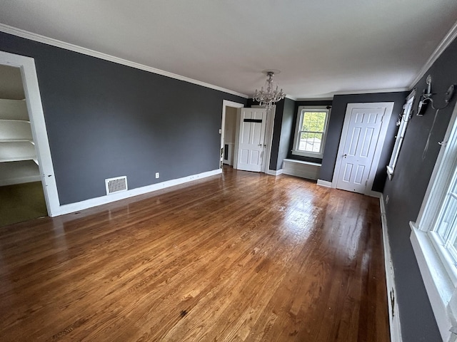 entrance foyer featuring crown molding, hardwood / wood-style floors, and a chandelier