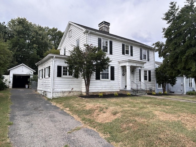 colonial-style house with a front yard, a garage, and an outdoor structure