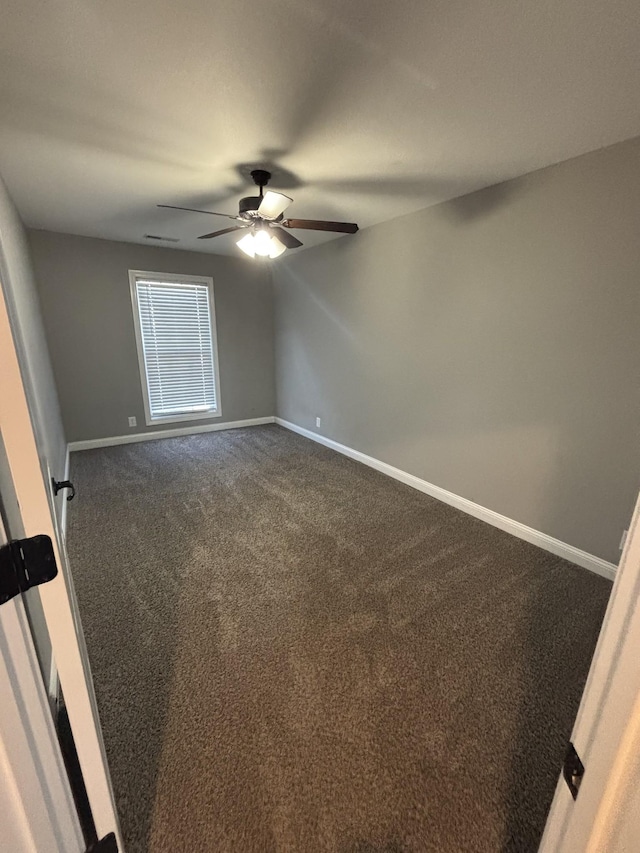 empty room with ceiling fan and dark carpet