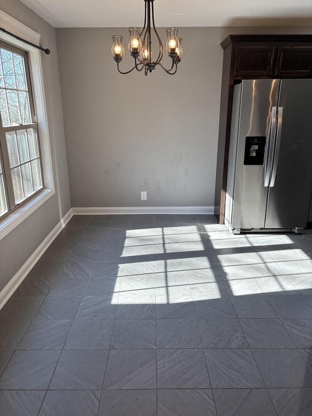 unfurnished dining area with an inviting chandelier and light tile patterned floors