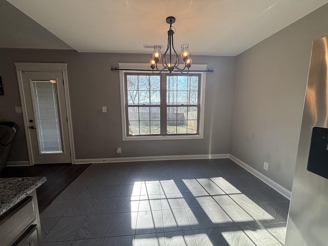 unfurnished dining area featuring an inviting chandelier and dark tile patterned floors