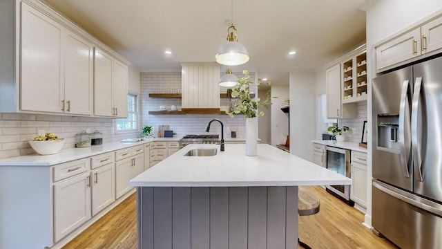 kitchen featuring sink, hanging light fixtures, tasteful backsplash, wine cooler, and stainless steel refrigerator with ice dispenser