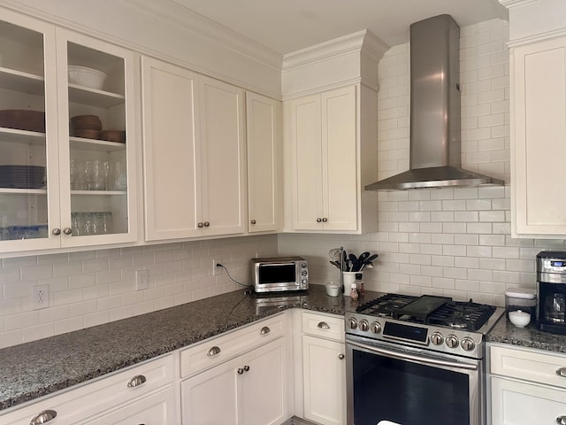 kitchen with stainless steel gas range, decorative backsplash, white cabinets, and wall chimney range hood